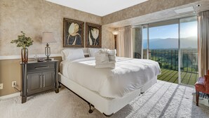 Une chambre spacieuse avec un grand lit, une table de chevet, une lampe et une vue sur l’extérieur grâce à une porte-fenêtre coulissante.