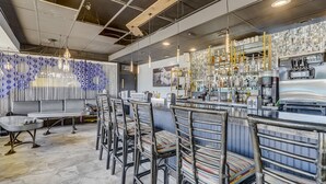 Un espace bar moderne doté d’un long comptoir, de tabourets de bar et d’une variété d’ustensiles et de bouteilles.