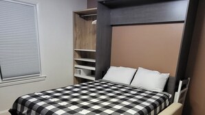 Un dormitorio moderno con cama, estanterías empotradas y una ventana con persianas.