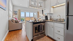 A modern kitchen with white cabinetry, stainless steel appliances, and a view to the outside.