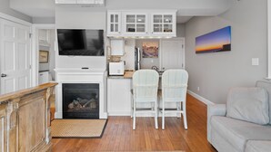 A compact living space with a fireplace, a TV, white cabinetry, and a painting on the wall.