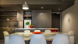 Una cocina moderna con una mesa de vidrio, sillas blancas y un tazón rojo.
