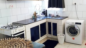 Una cocina compacta con estufa a gas, lavadora y pileta.