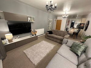 Relax in this stylish living room with a flat-screen TV, comfortable sofa, and dining area for four.