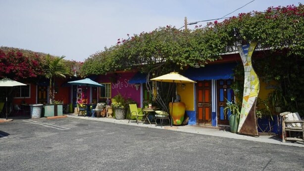 A colorful building with outdoor seating and a large yellow umbrella. - VILLA BRASIL MOTEL (Los Angeles)