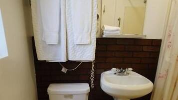 A small bathroom with a toilet, a sink, and a mirror. There are towels hanging on a rack above the toilet.