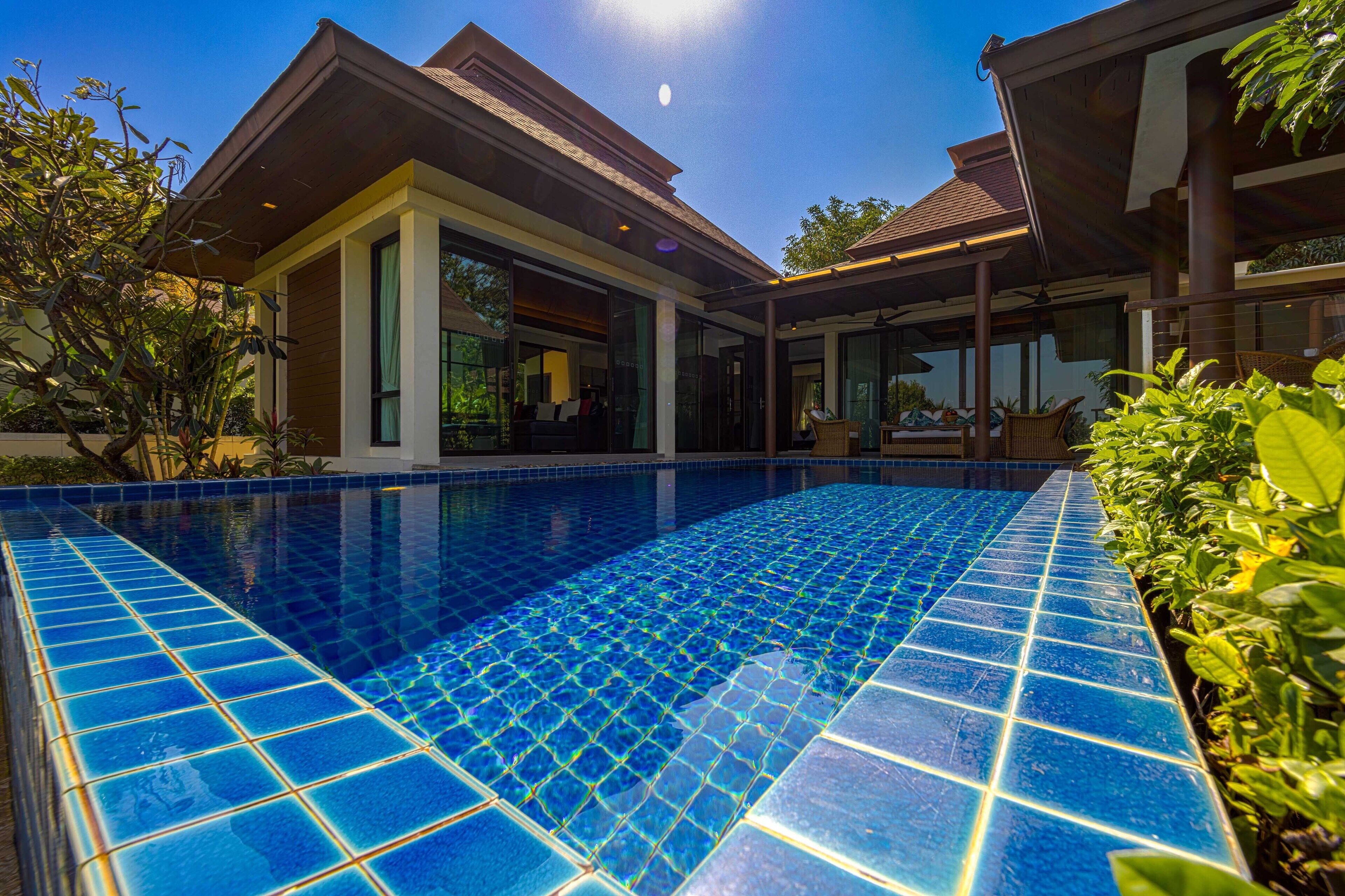 A modern house with a swimming pool, large windows, and a covered patio area.