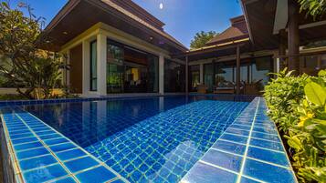 A modern house with a swimming pool, large windows, and a covered patio area.