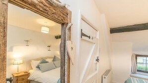 A bedroom with a bed, bedside table, lamp, and a window.