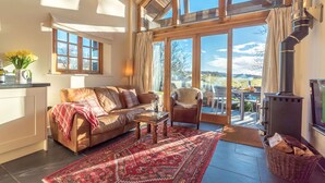 Ein gemütliches Wohnzimmer mit einer Ledersofa, einem gemusterten Teppich und einem großen Fenster mit Blick auf eine reizvolle Landschaft.
