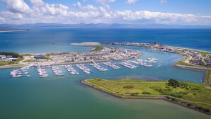 An aerial view of a marina with numerous boats docked, surrounded by water and greenery.