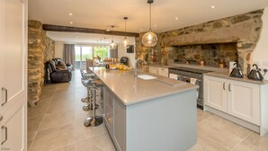 A spacious kitchen with a large island, stone walls, and modern lighting.