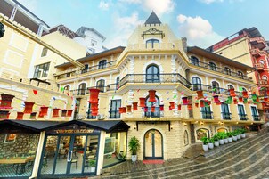 Un edificio histórico con una torre central, varios balcones y una cafetería en la planta baja.