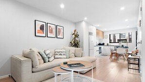 A modern living room with a sofa, coffee table, and dining area with chairs and a table. - The Oasis - Sauna | Parking | Fast WiFi | Airport (Mangere Bridge)