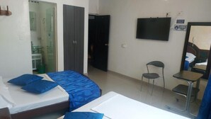 A hotel room with two beds, a desk, a chair, a TV, and a bathroom visible through an open door. - Hotel Perla Azul (Girardot)