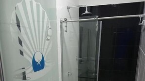 A bathroom with a glass shower enclosure, a toilet, and a glass door with a logo. - Hotel Perla Azul (Girardot)