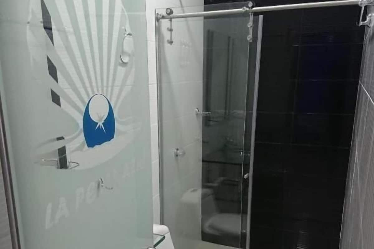 Un baño con cabina de ducha de vidrio, inodoro y puerta de vidrio con un logotipo.
