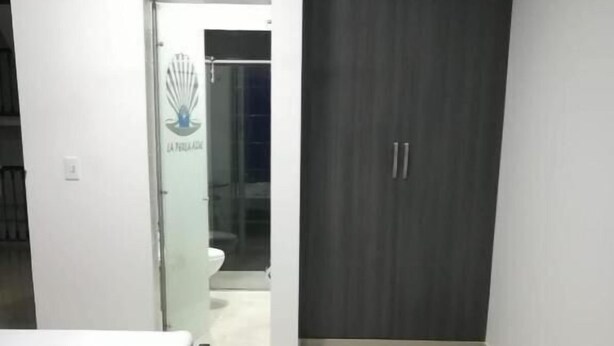 A bedroom with a bed, a wardrobe, and a bathroom visible through an open door. - Hotel Perla Azul (Girardot)