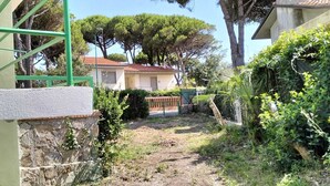 A residential property with a stone wall, a green metal gate, and a house with a red roof. - Villa Eusepia, facing the beach of Tirrenia  (Marina di Pisa-tirrenia-calambr)