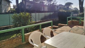 A patio area with outdoor seating, a green railing, and a view of a tennis court and residential buildings in the background. - Villa Eusepia, facing the beach of Tirrenia  (Marina di Pisa-tirrenia-calambr)