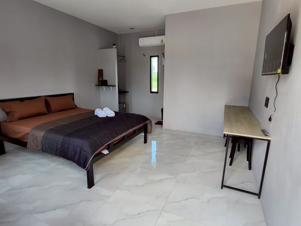 A bedroom with a bed, a desk, and a TV.
