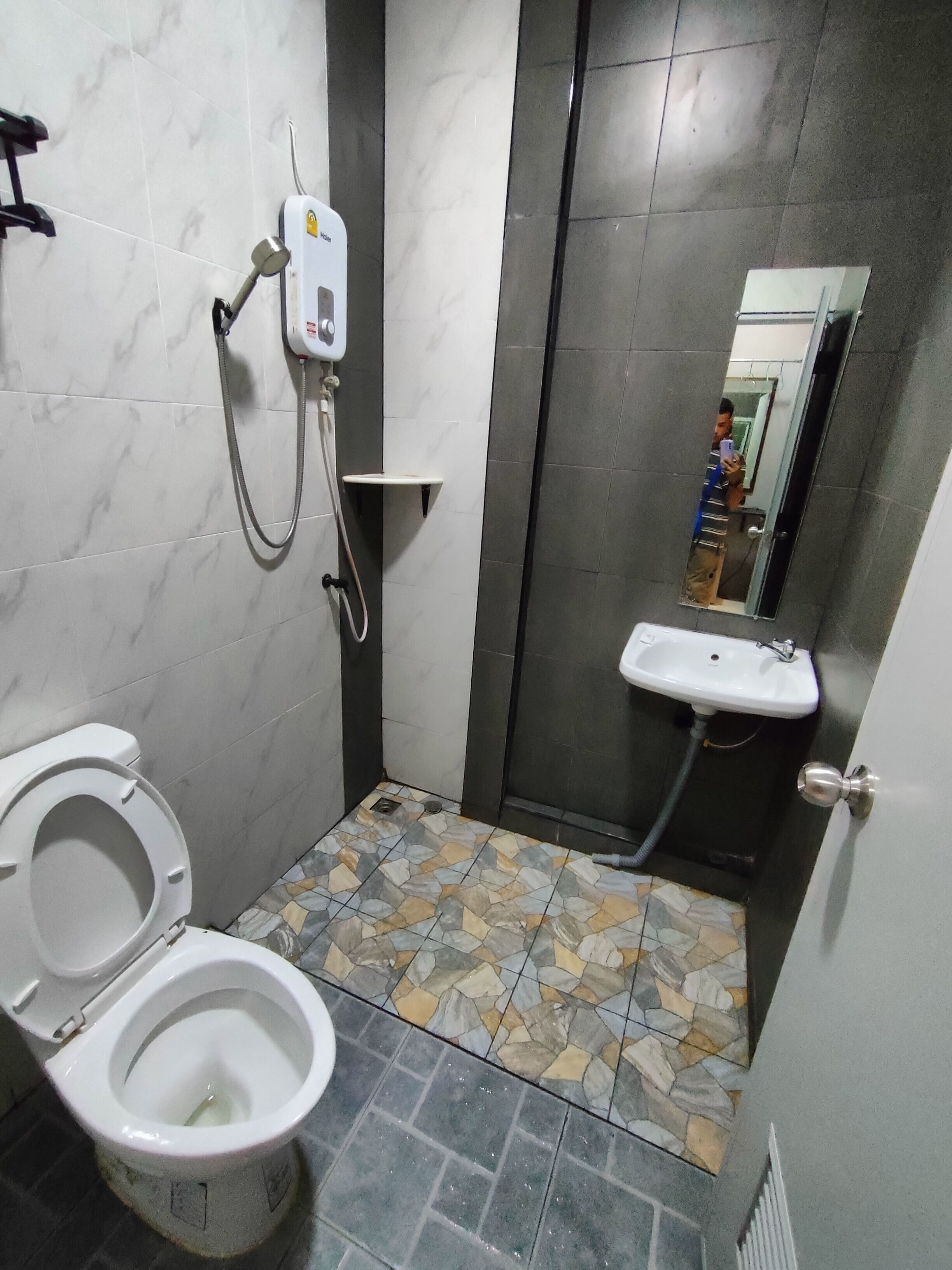 A bathroom with a toilet, a sink, a shower, and a mirror.
