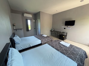 A hotel room with two beds, a TV, a desk with a chair, and an air conditioning unit. - Check-in Resort (Chai Nat)