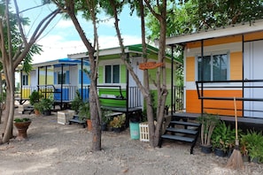 A row of colorful mobile homes with outdoor seating and potted plants.
