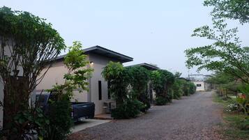 A residential street with houses, a gravel driveway, and lush greenery.