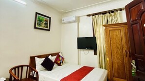 A hotel room with a bed, a wooden chair, a TV, an air conditioning unit, and a wardrobe. - Hoang Duong Hotel by Bay Luxury (Hanoi)