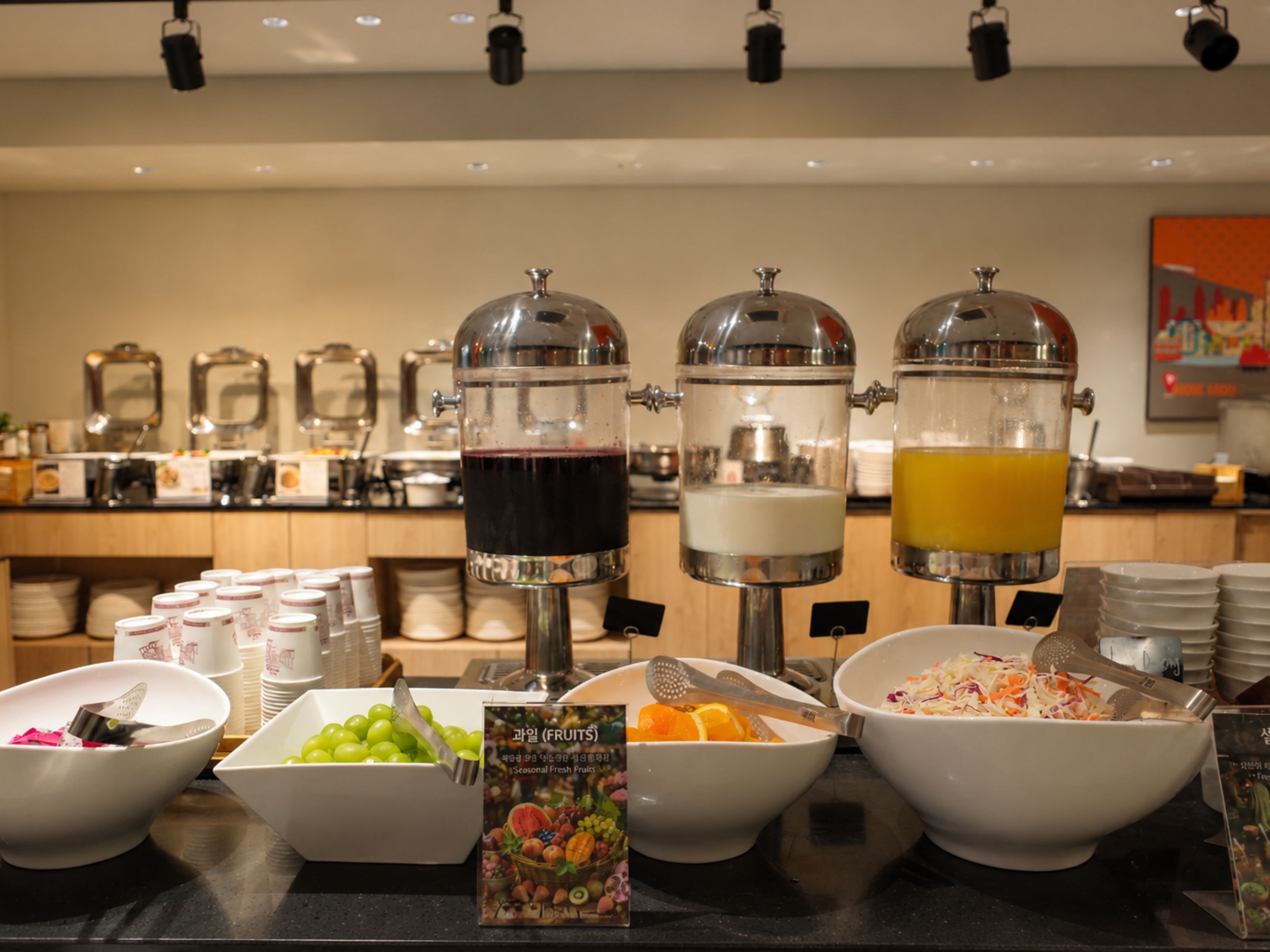 A buffet setup with beverage dispensers and various food bowls.