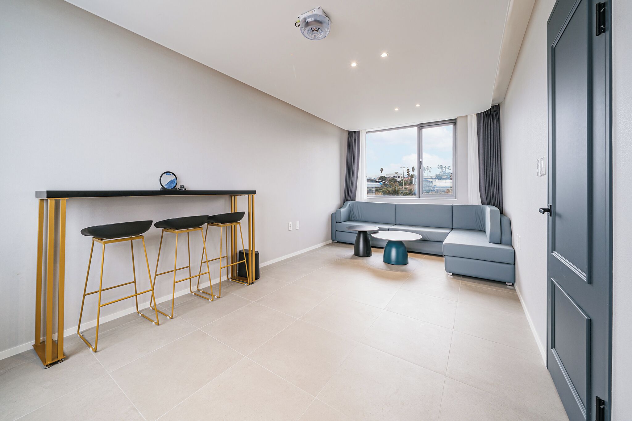 A modern living room with a sofa, a coffee table, and a bar area with stools.