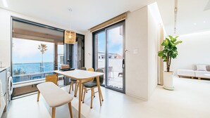 Un soggiorno moderno con un'ampia finestra, un'area pranzo con tavolo e sedie, e un divano.