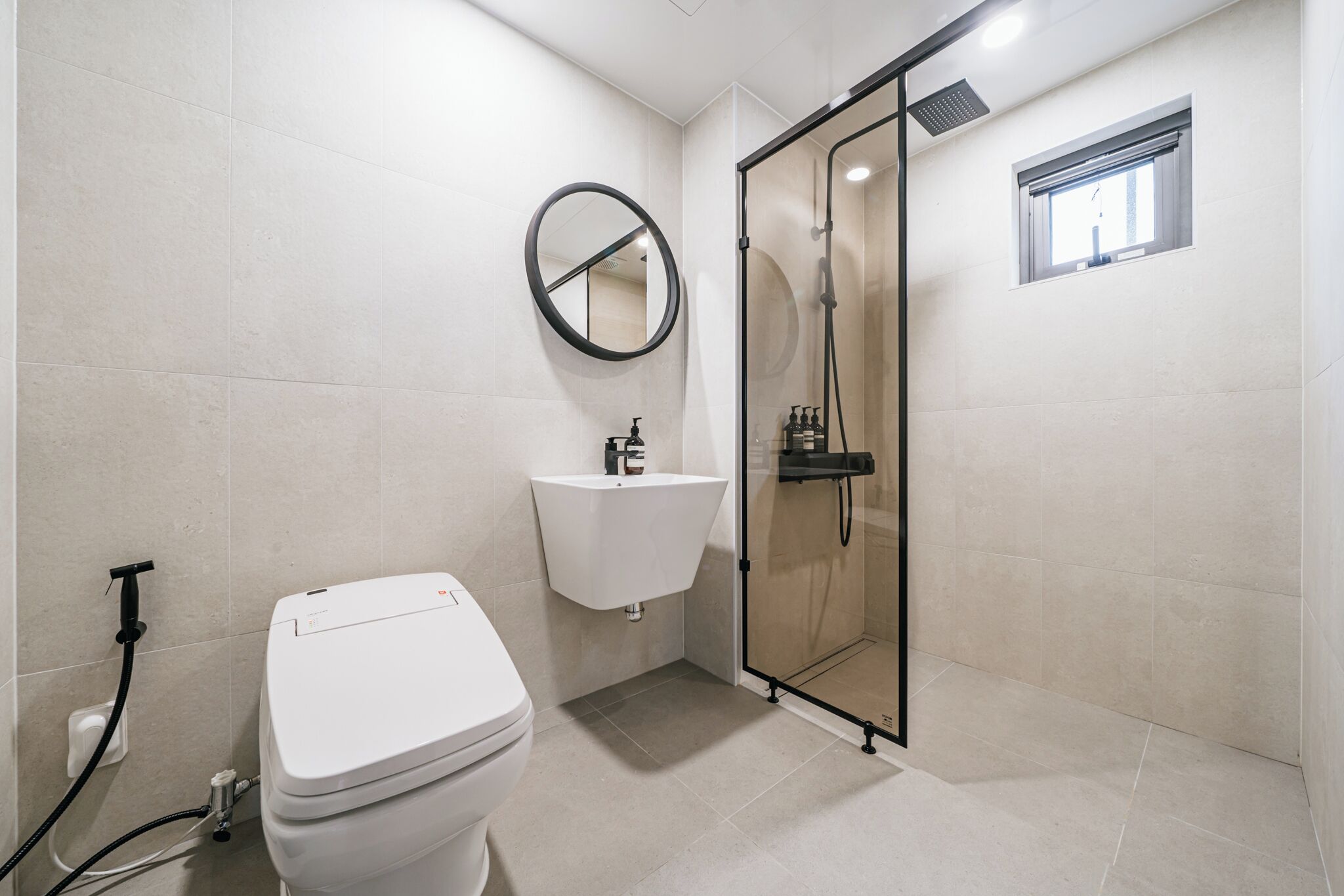 A modern bathroom with a toilet, sink, and glass shower enclosure.