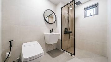 A modern bathroom with a toilet, sink, and glass shower enclosure.