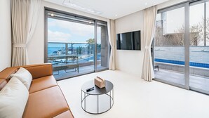 Una camera d'hotel moderna con un'ampia finestra, un divano, un tavolino rotondo e un televisore a schermo piatto.