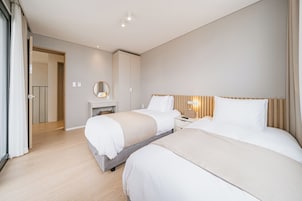 A hotel room with two beds, a bedside table, a mirror, and a wardrobe.