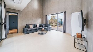 Un soggiorno moderno con un divano componibile, un tavolino da caffè, una TV a schermo piatto e un'ampia finestra con vista.