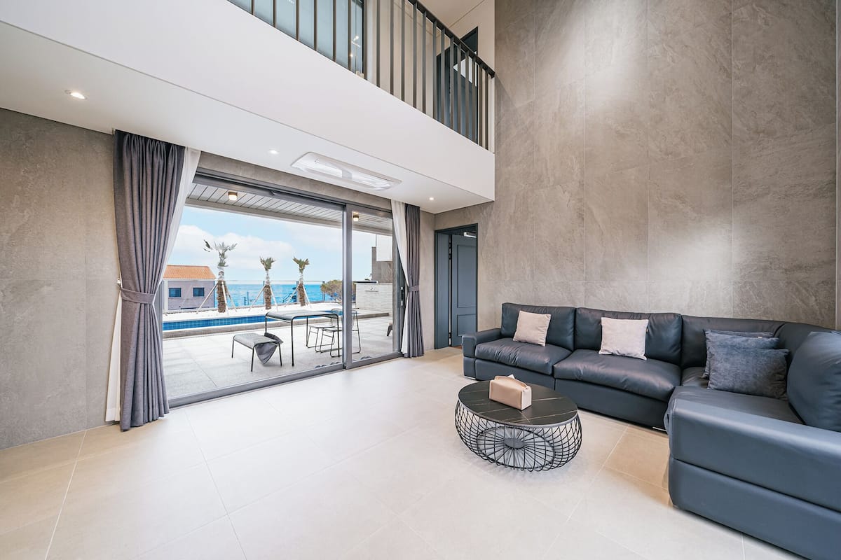 Un salon moderne avec un canapé, une table basse et une vue sur une piscine.