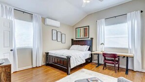 A bedroom with a bed, a desk, a chair, and a ceiling fan.