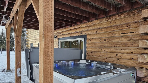 A hot tub in a log cabin with a wooden exterior and a metal frame. - Log Cabin with Mountains and Lake View, enjoy relaxing in the hot tub (Clam Gulch)