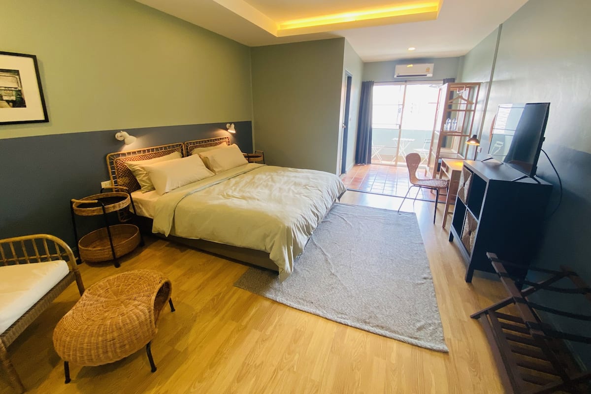 Quarto com cama, televisão, escrivaninha e cadeira.