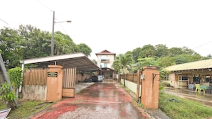 A gated entrance with a paved pathway leading to a building with a red roof. - OYO 90915 Ilham Villa (Kota Bharu)