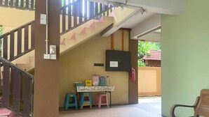 A staircase with pink triangular decorations, a table with a patterned tablecloth, and a wooden bench. - OYO 90915 Ilham Villa (Kota Bharu)