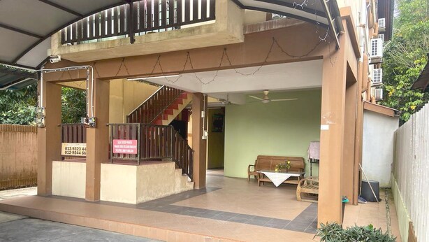 A covered outdoor area with a staircase leading to a second floor, a bench, and a table with a vase of flowers. - OYO 90915 Ilham Villa (Kota Bharu)