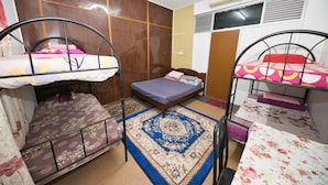 A dormitory room with bunk beds, a wooden wardrobe, a patterned rug, and an air conditioning unit. - OYO 90915 Ilham Villa (Kota Bharu)