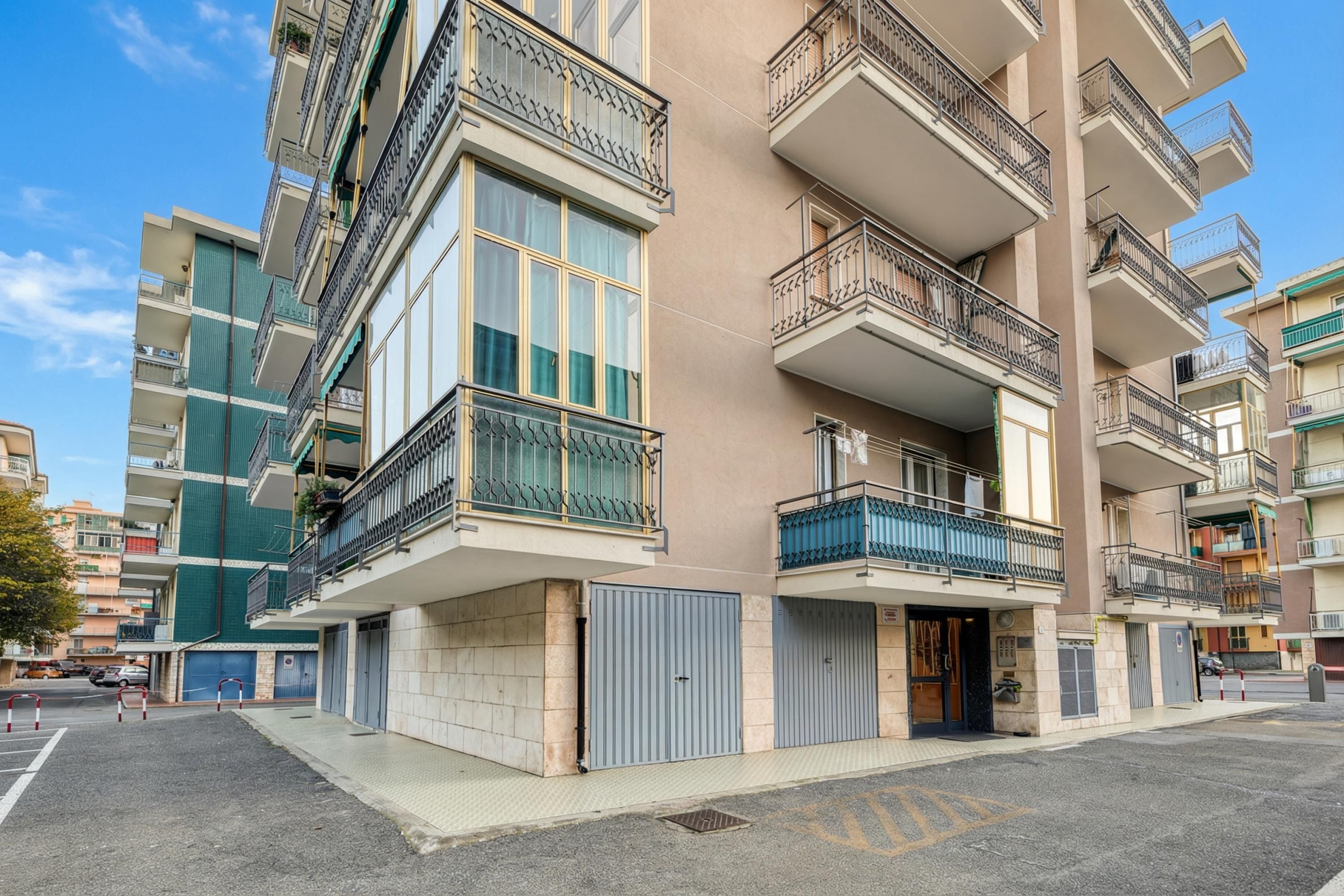 Un edificio residenziale a più piani con balconi, ampie finestre e un ingresso chiuso da cancello.