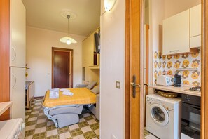 Une chambre d’hôtel de taille réduite, équipée d’un lit, d’une machine à laver et d’une kitchenette.