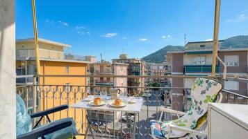 Un balcone con un tavolo apparecchiato per due, una sedia e vista sulla città.