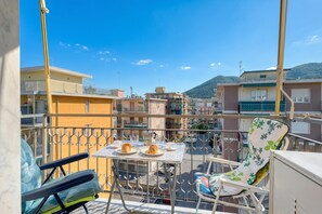 Un balcon avec une table dressée pour deux personnes, une chaise et une vue sur le paysage urbain.